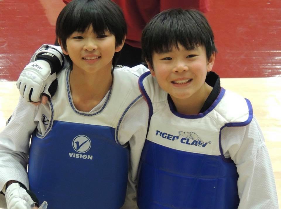 Two young Sparta Taekwondo students smiling together at a tournament — building confidence and character through martial arts in Walnut Creek.